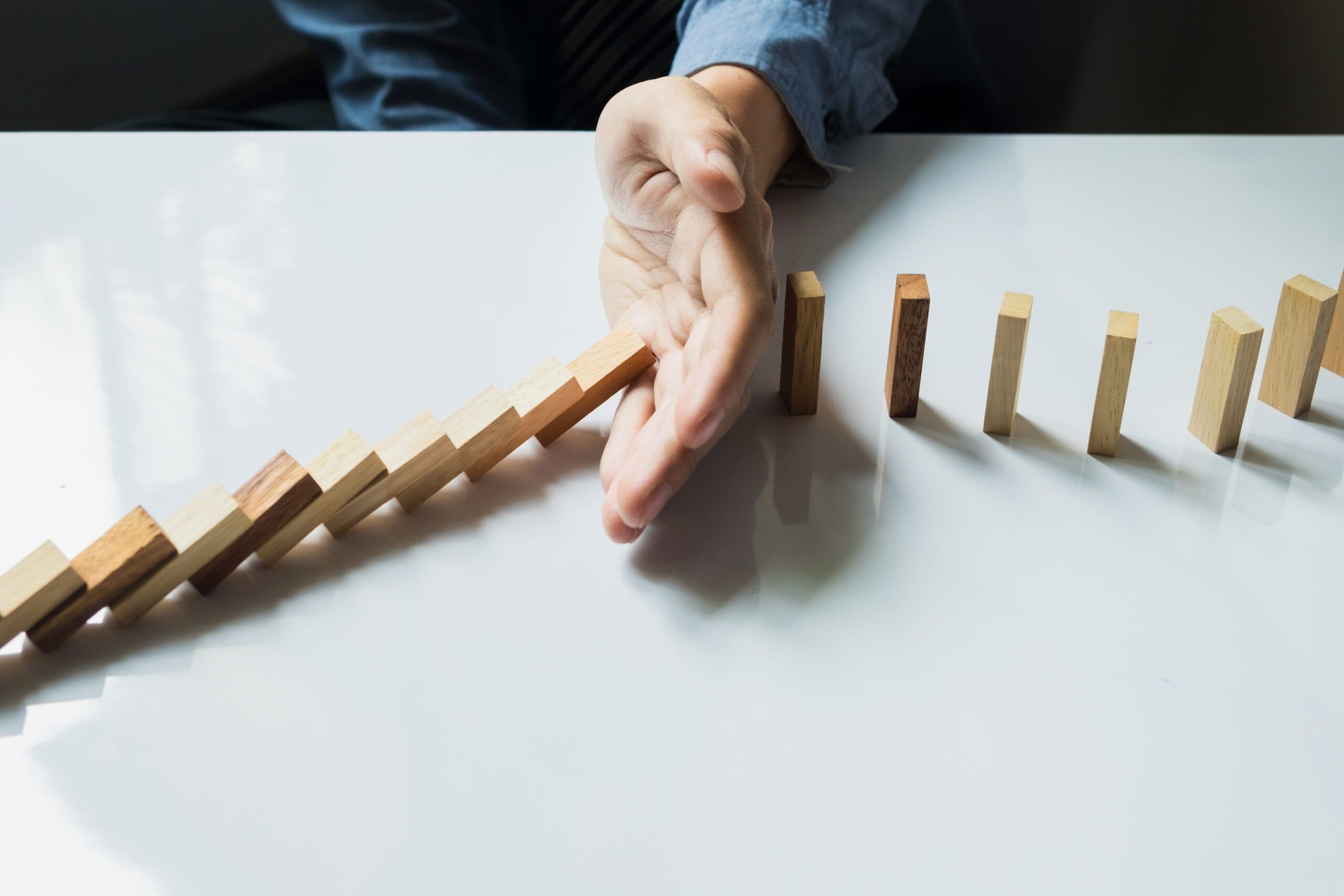 Businessman hand stop dominoes continuous toppled or risk with c